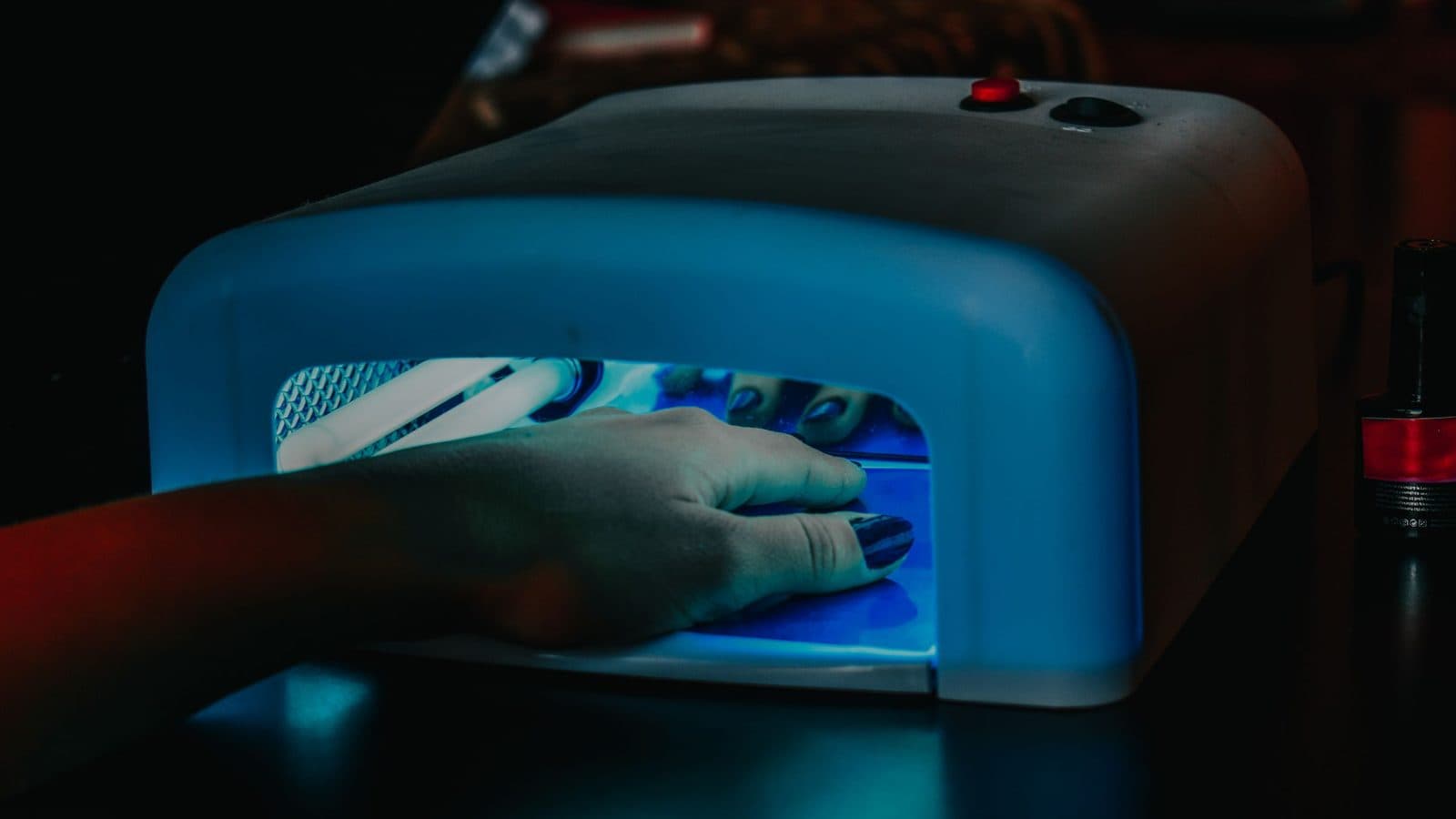 A hand curing inside a UV nail lamp during a gel application