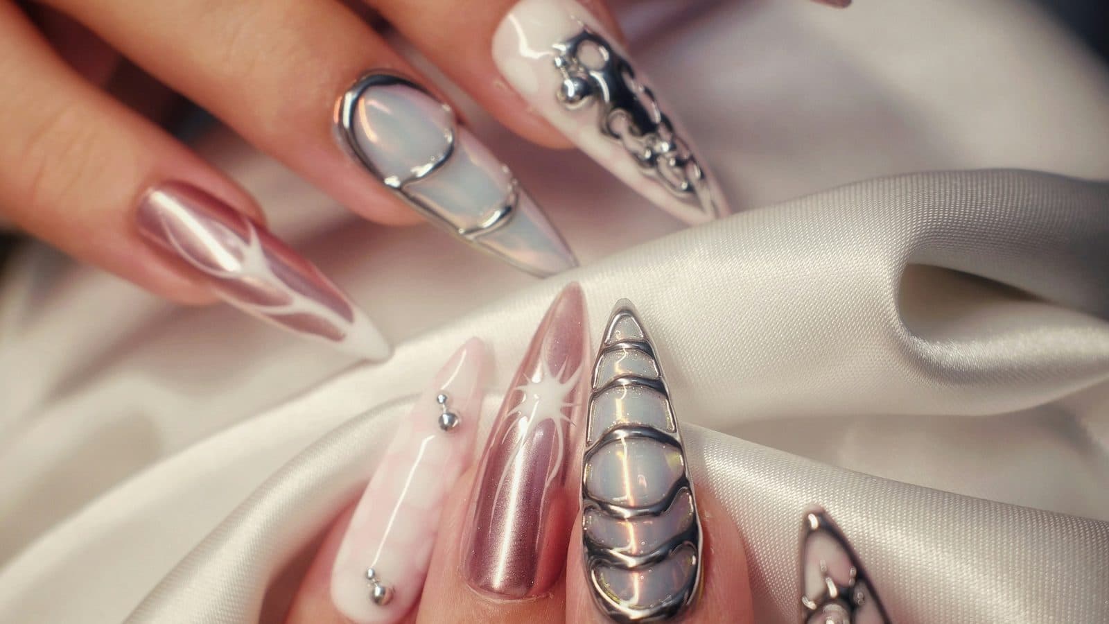 Long stiletto nails finished in mirror chrome and pearl gel with liquid-metal detailing