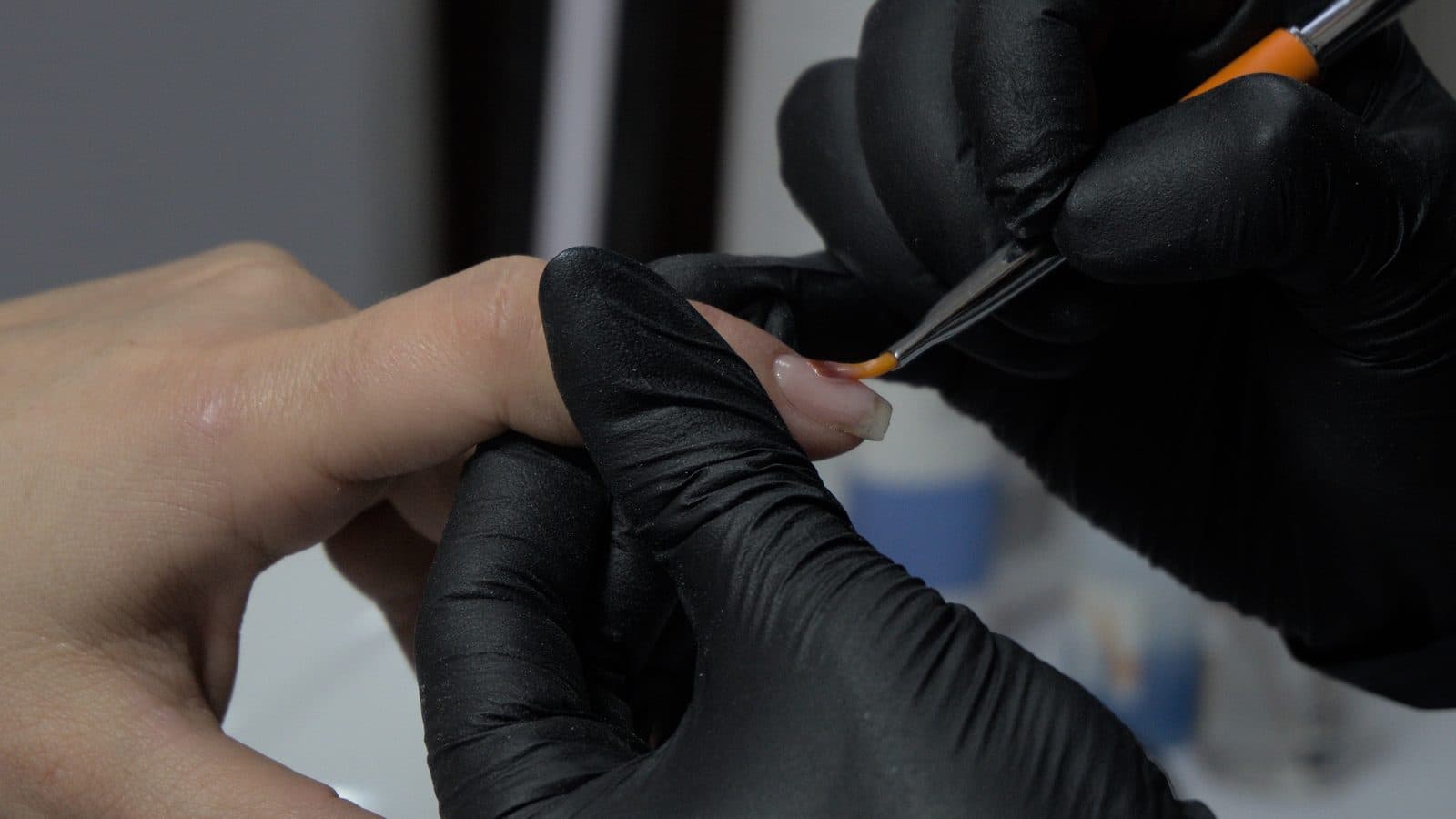 Nail technician preparing a client's nail plate before applying gel base coat